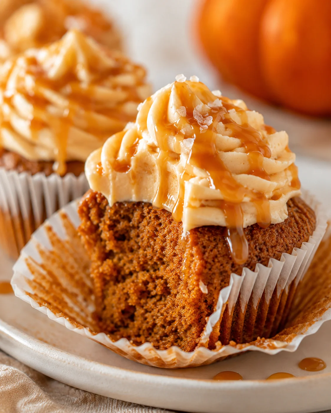 Close-up of pumpkin cupcakes topped with caramel cream cheese frosting and drizzled caramel