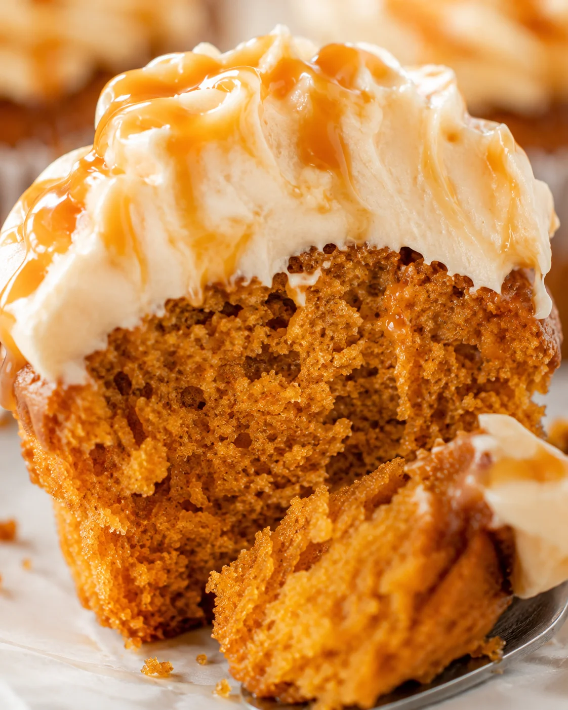 Close-up of pumpkin cupcakes topped with caramel cream cheese frosting and drizzle