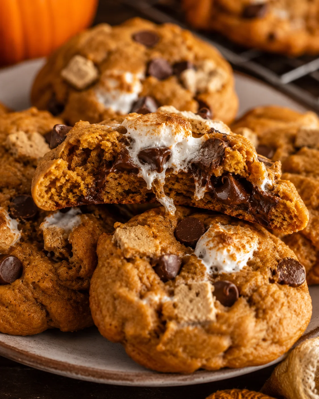 Close-up of soft pumpkin s’mores cookies with melted marshmallows and chocolate.