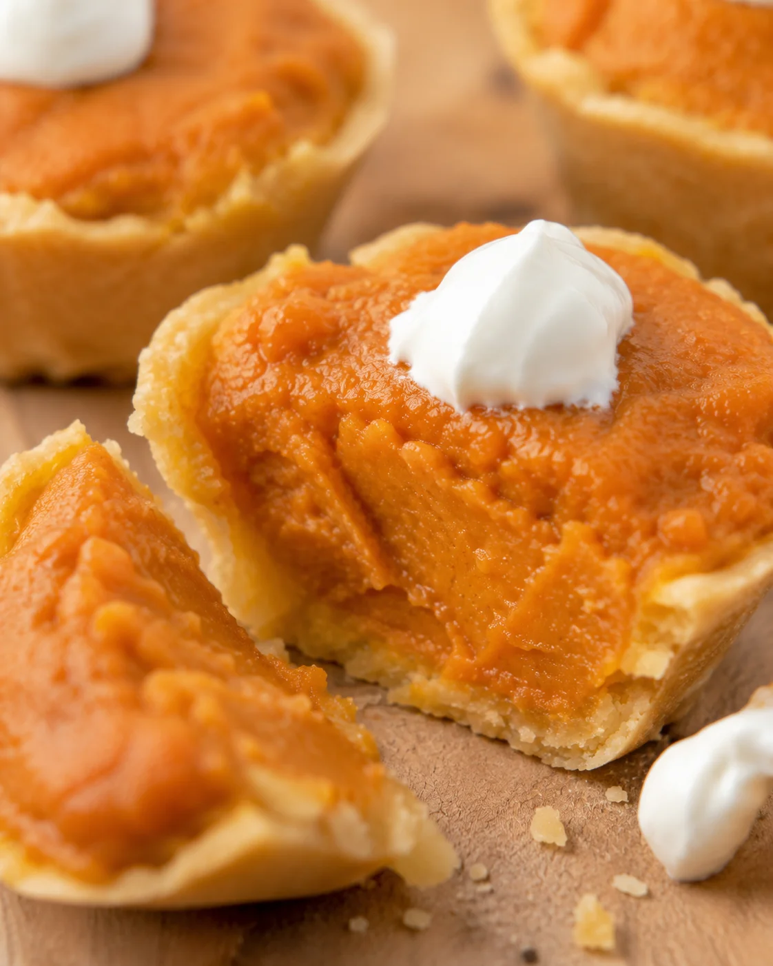 Mini pumpkin pies with yogurt topping for dogs on a wooden surface.