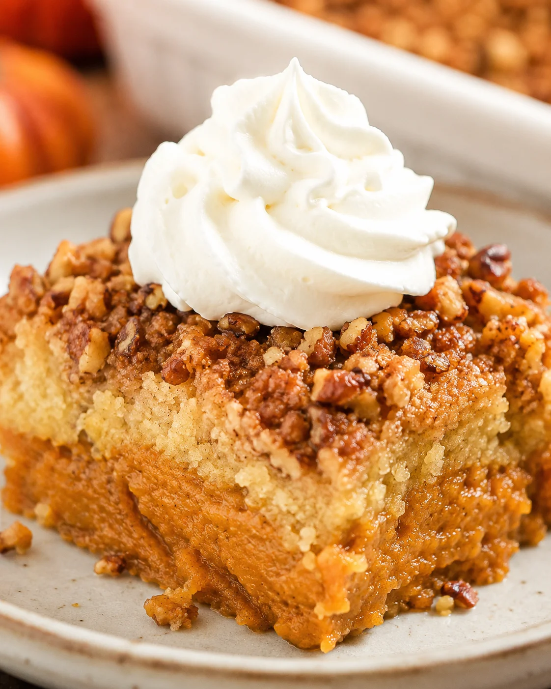 Delicious pumpkin dump cake topped with whipped cream and crunchy nuts