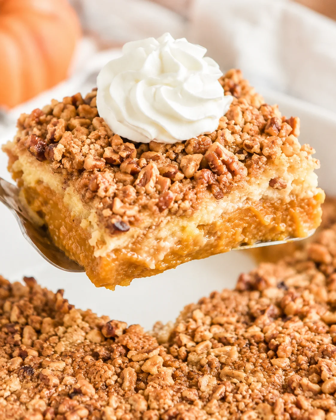 A slice of pumpkin dump cake topped with whipped cream and chopped nuts.