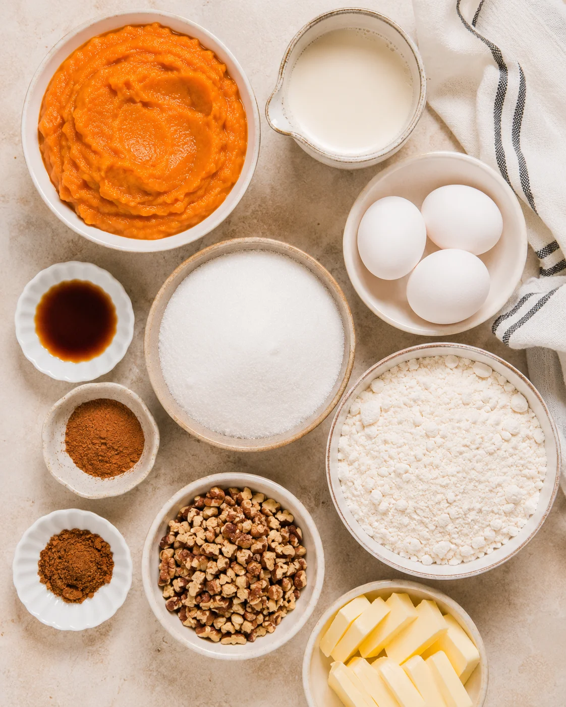 Assorted ingredients for pumpkin dump cake including pumpkin puree, eggs, and spices.
