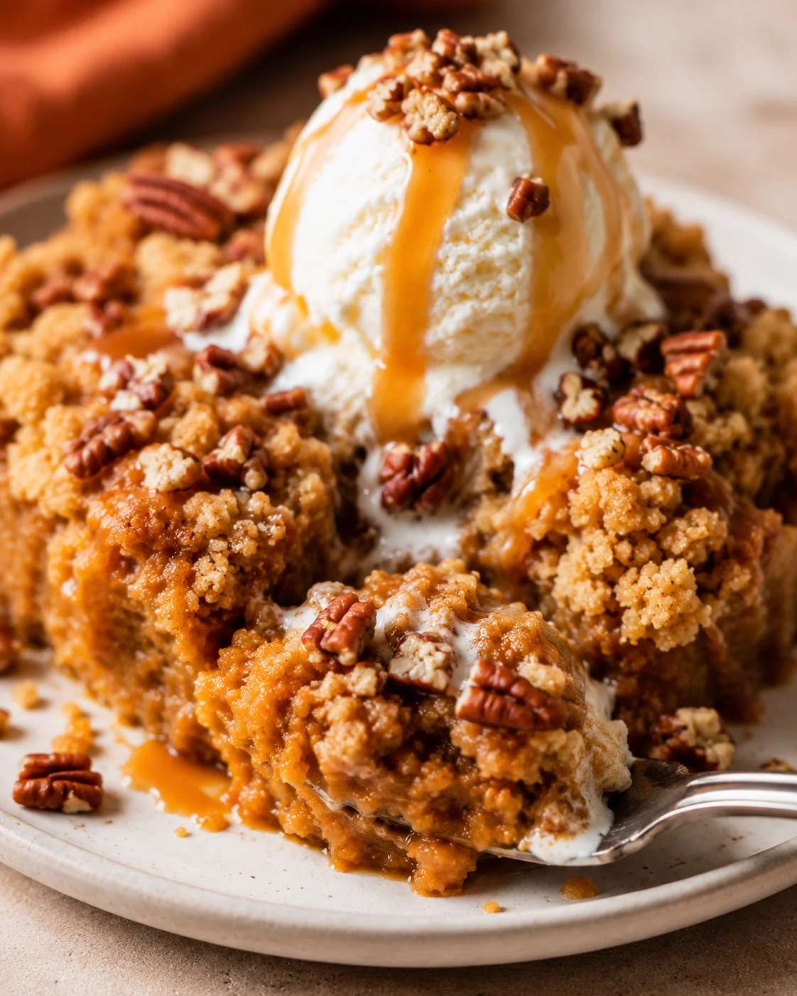 Close-up of warm pumpkin dump cake topped with vanilla ice cream and pecans