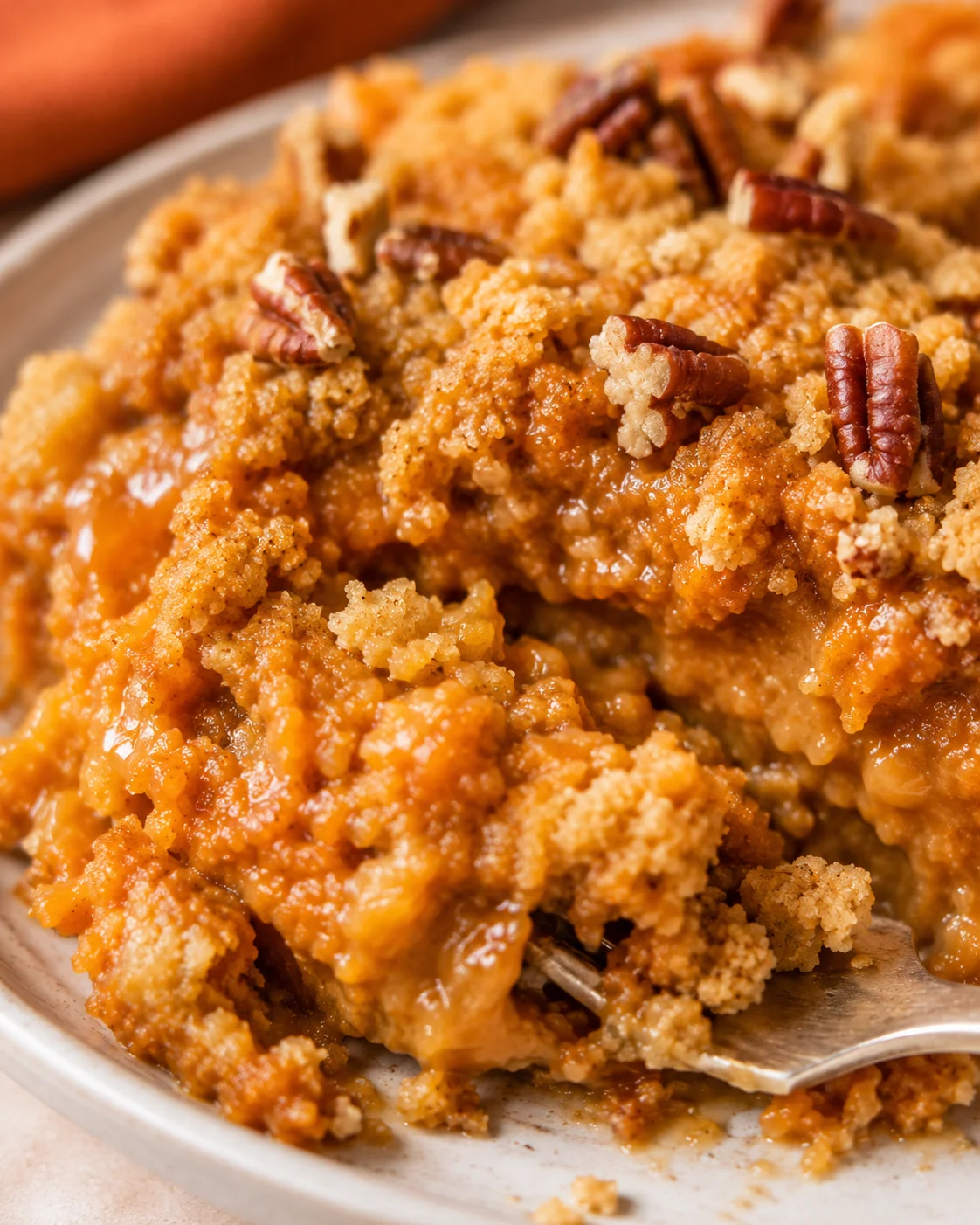 Close-up of a warm, crumbly pumpkin dump cake with pecans on top.
