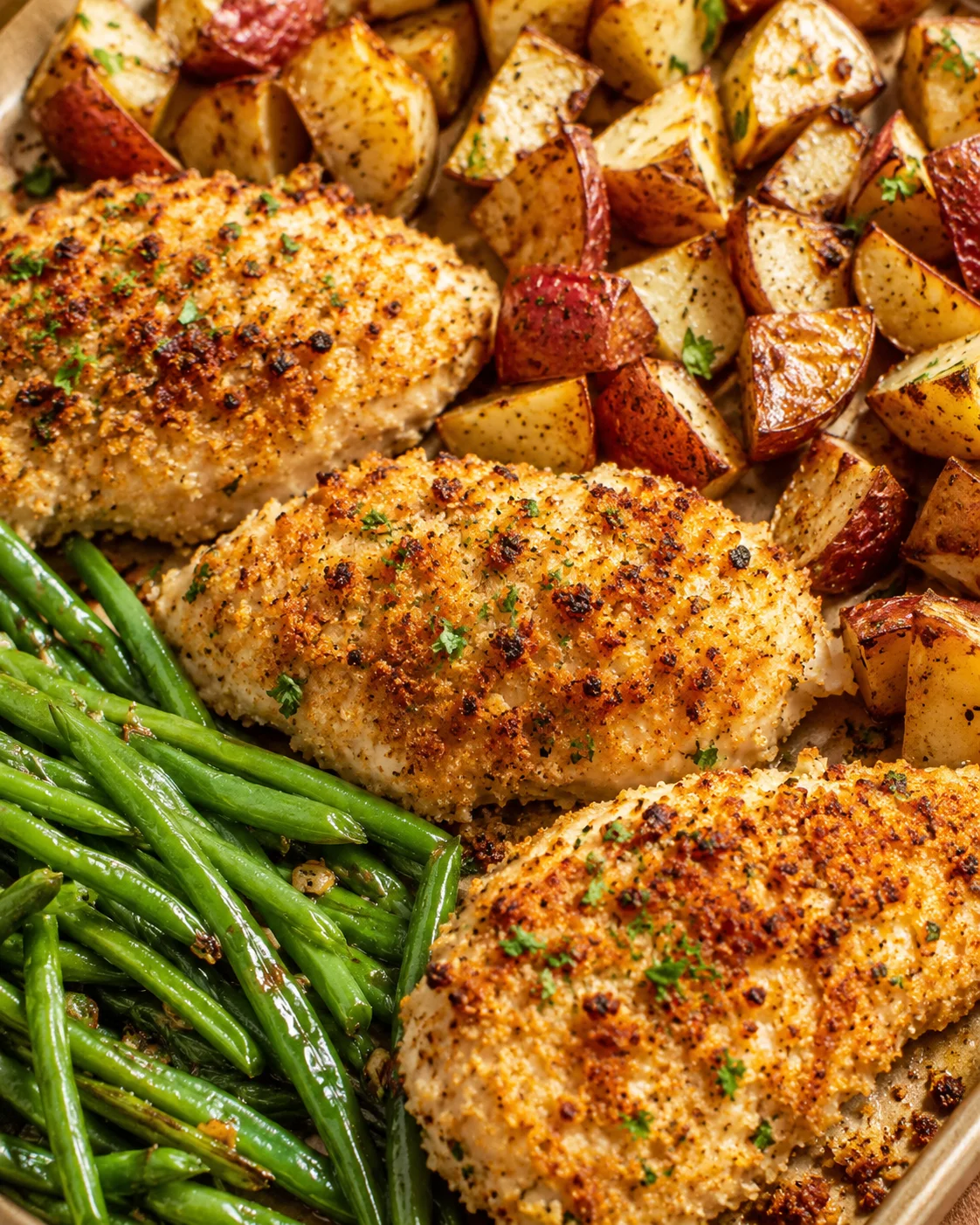 Crispy Parmesan-coated chicken with roasted potatoes and green beans on a sheet pan