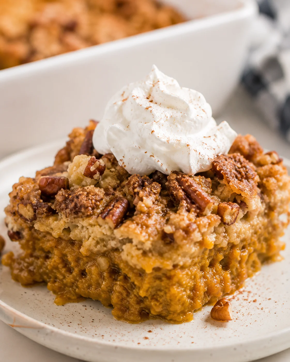 Close-up of a slice of pumpkin dump cake topped with whipped cream.