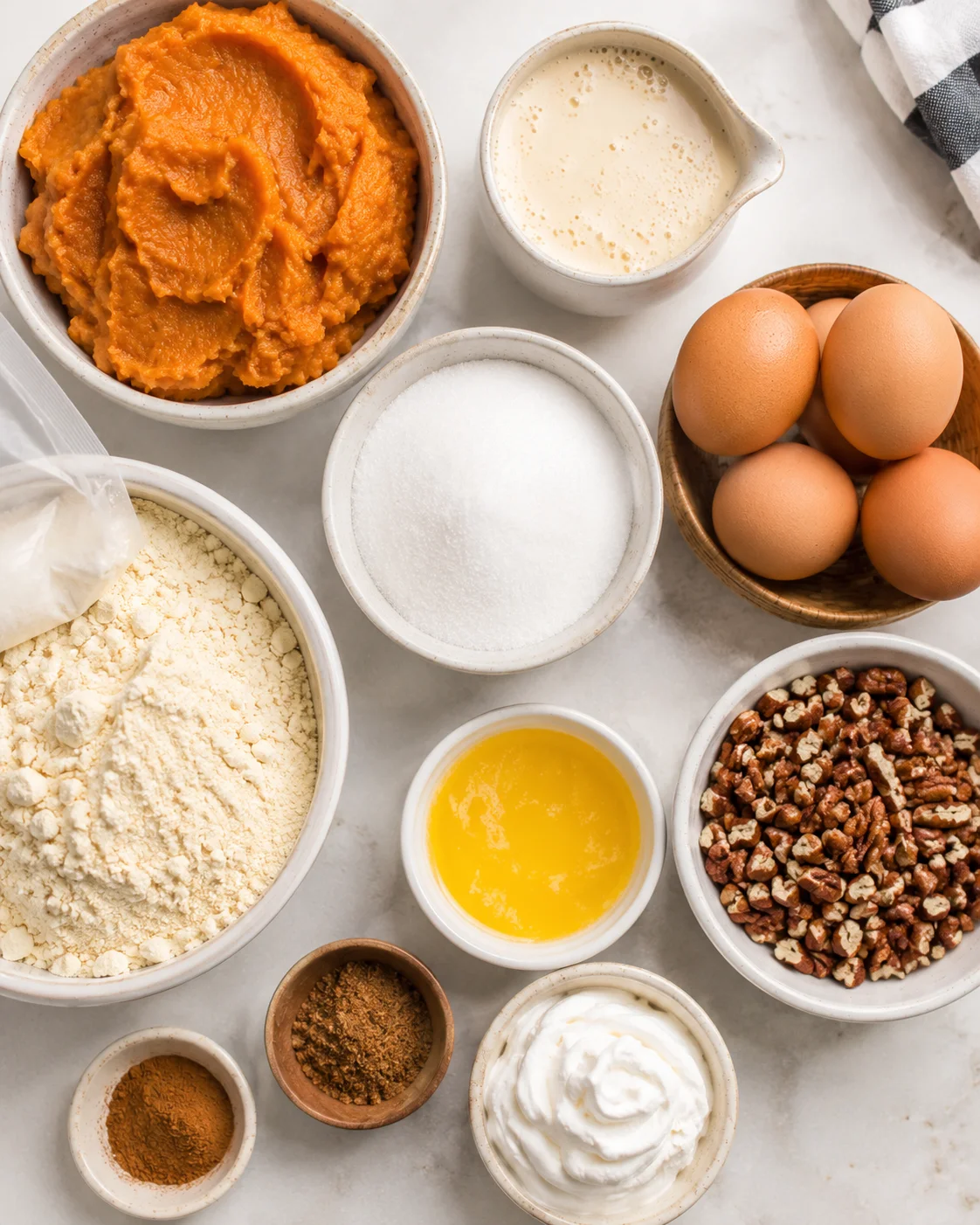 Various ingredients for pumpkin dump cake including pumpkin, eggs, sugar, and nuts.