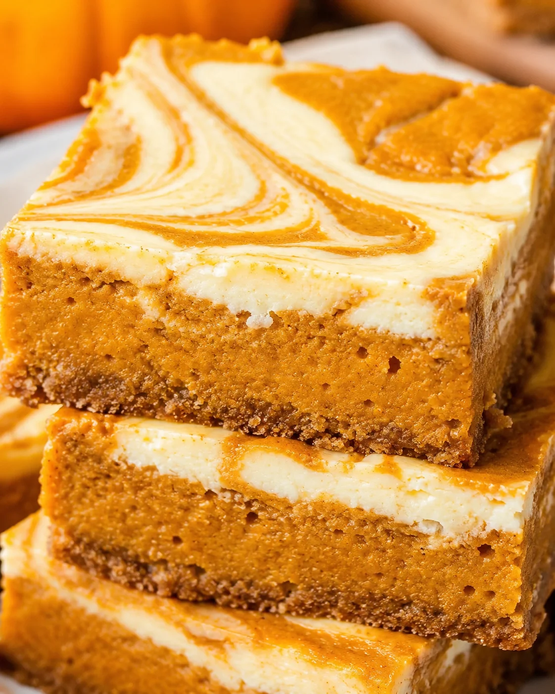 Close-up of marbled pumpkin cheesecake bars with swirls and a buttery crust