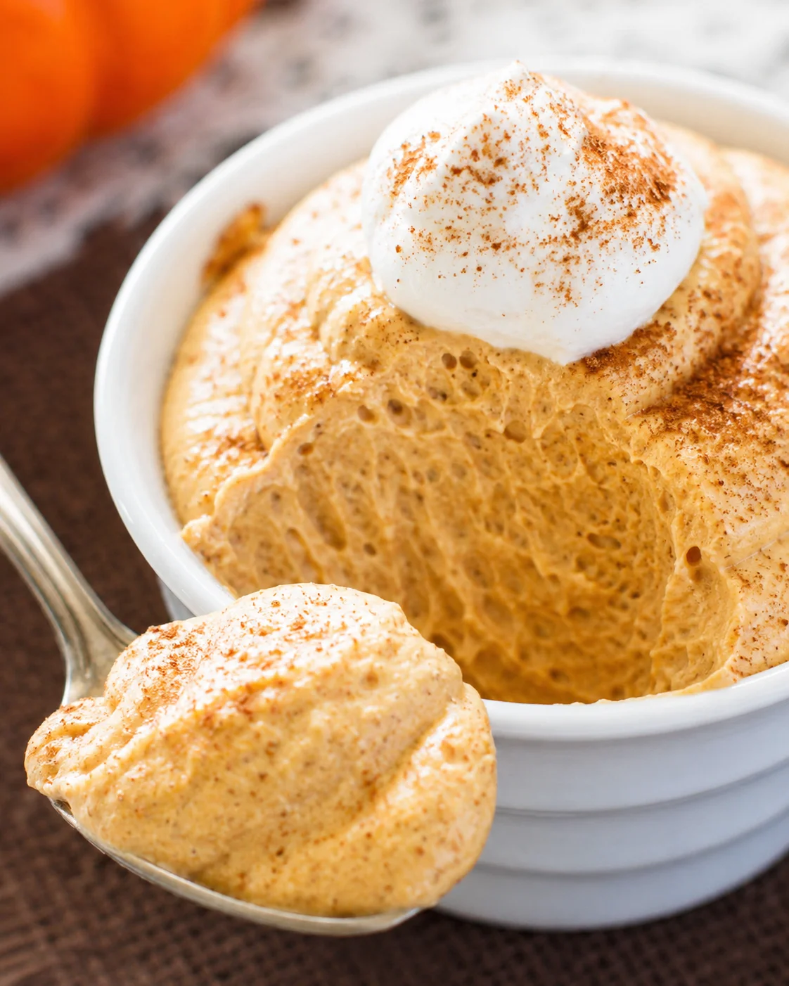Creamy pumpkin mousse topped with whipped cream and sprinkled with cinnamon.