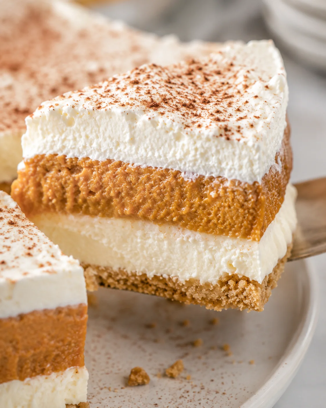 Close-up of a delicious layered no bake pumpkin pie slice with whipped topping and spices