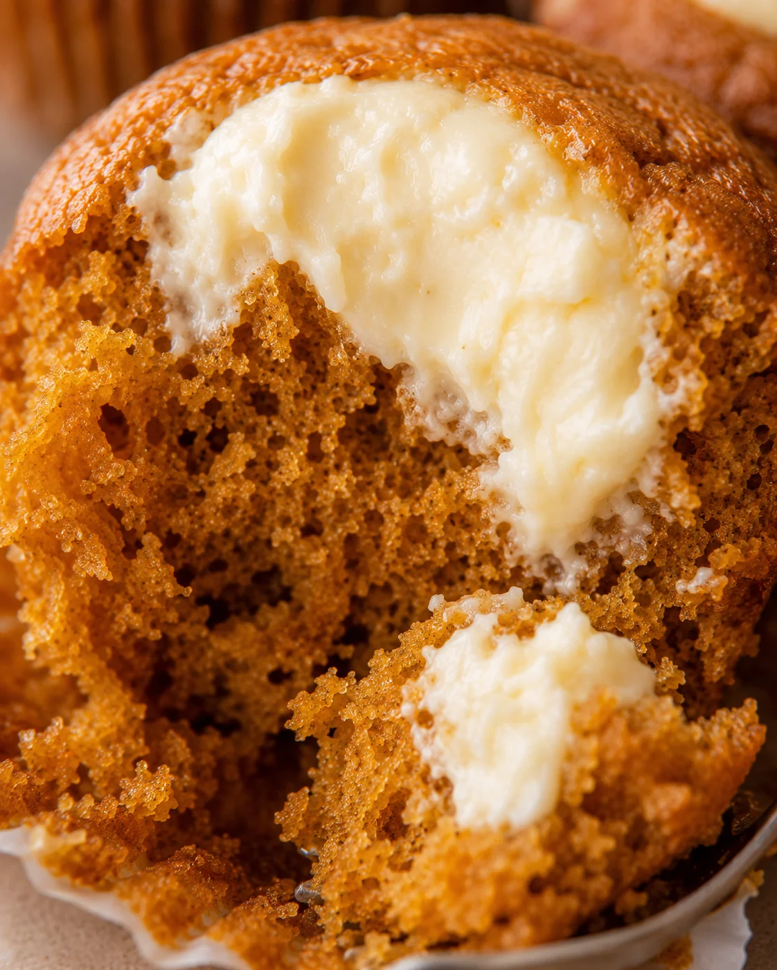 Close-up of a fluffy pumpkin muffin with creamy filling spilling out