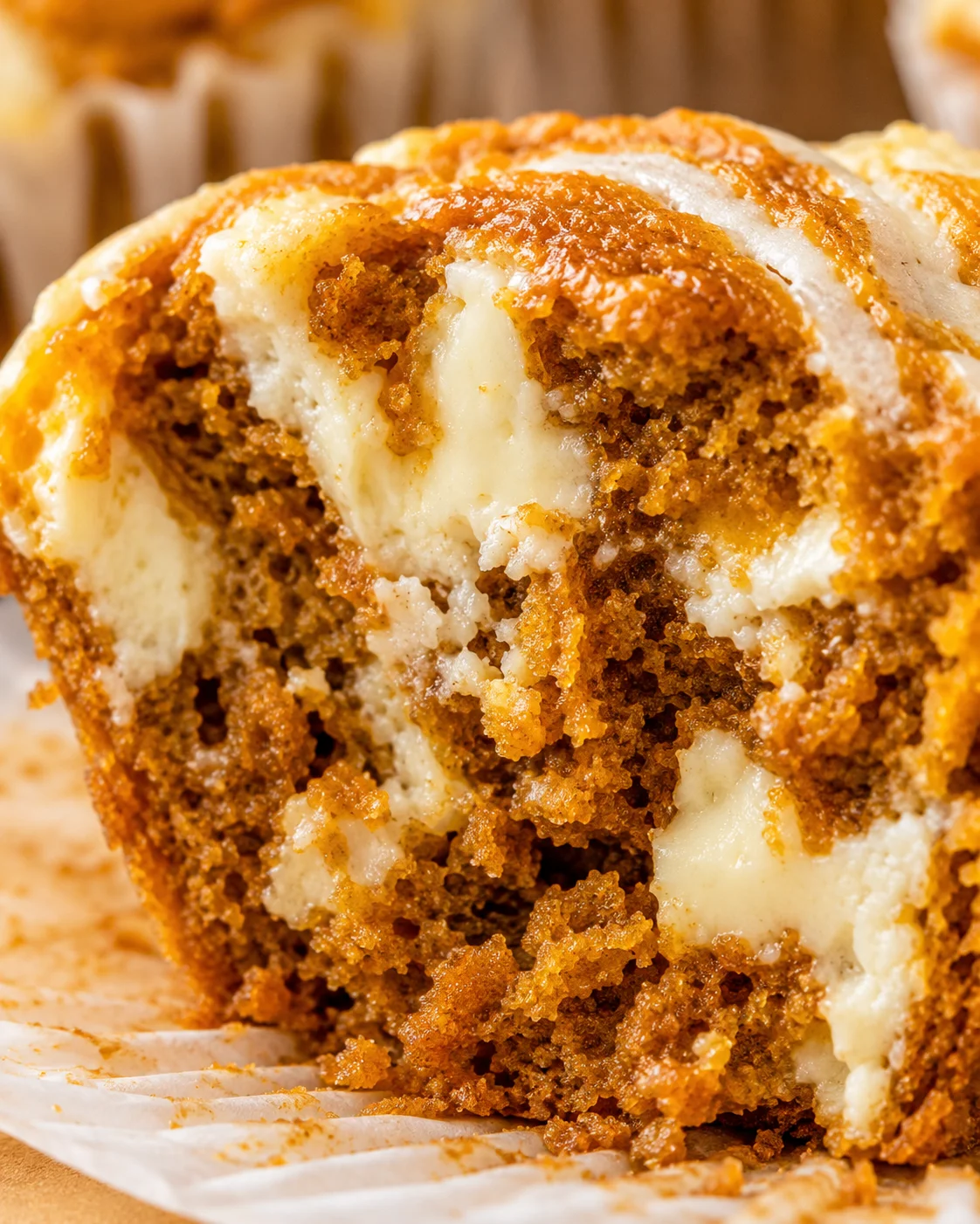 Close-up of moist pumpkin muffins topped with creamy swirl and golden brown crust.