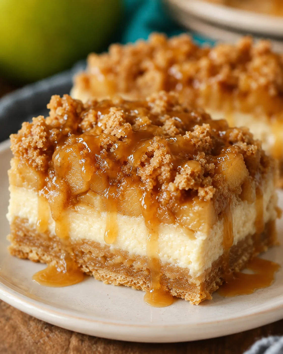 Close-up of caramel-topped apple pie cheesecake bars on a plate.