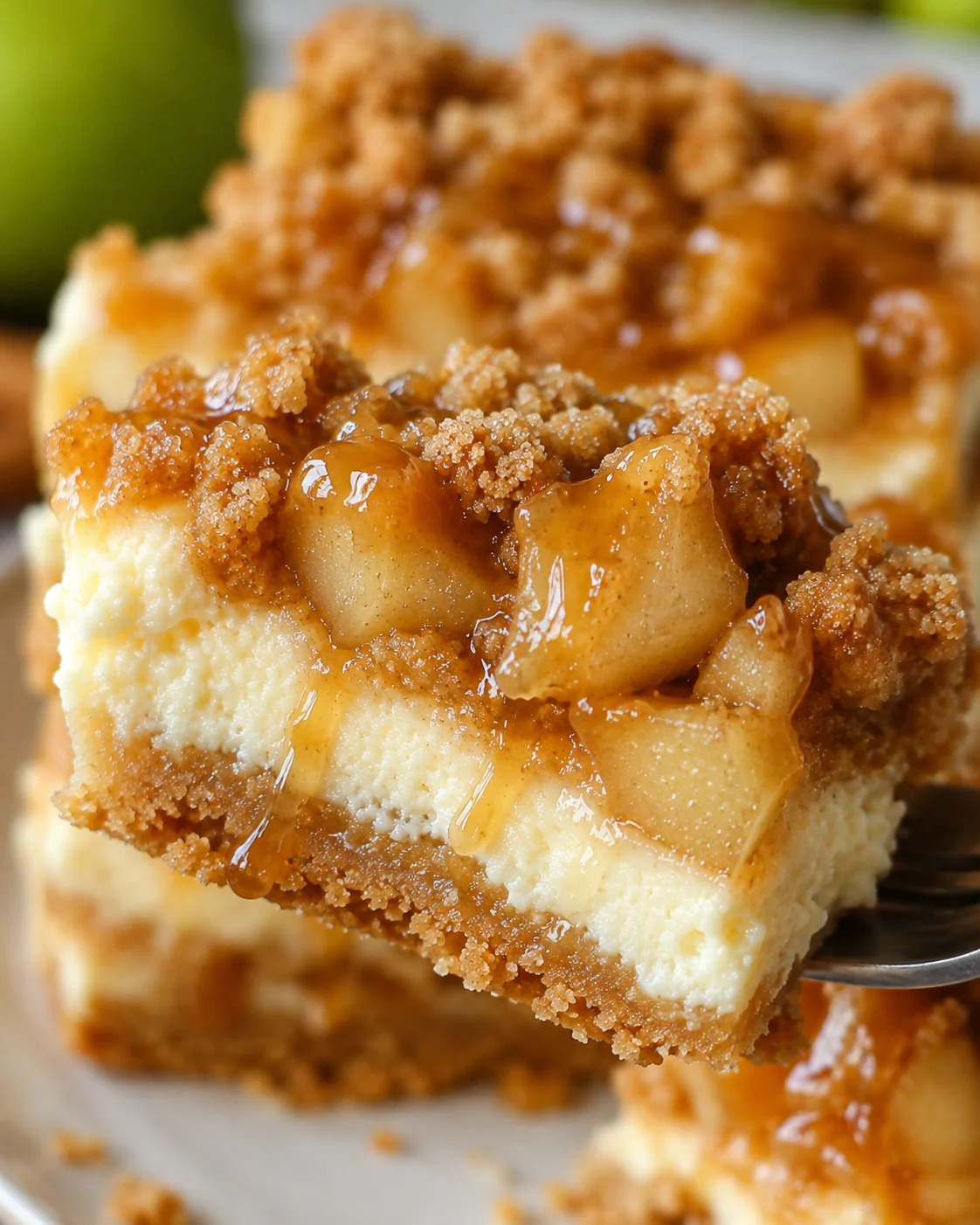 Close-up of caramel apple pie cheesecake bars with crumb topping and caramel drizzle.