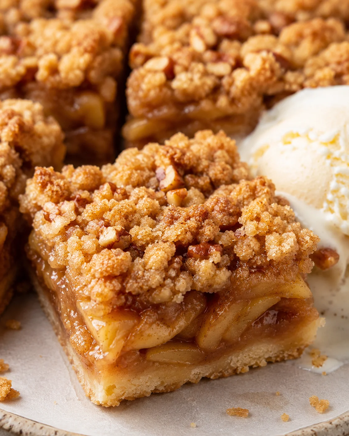 Close-up of apple pie bars with crumb topping and vanilla ice cream