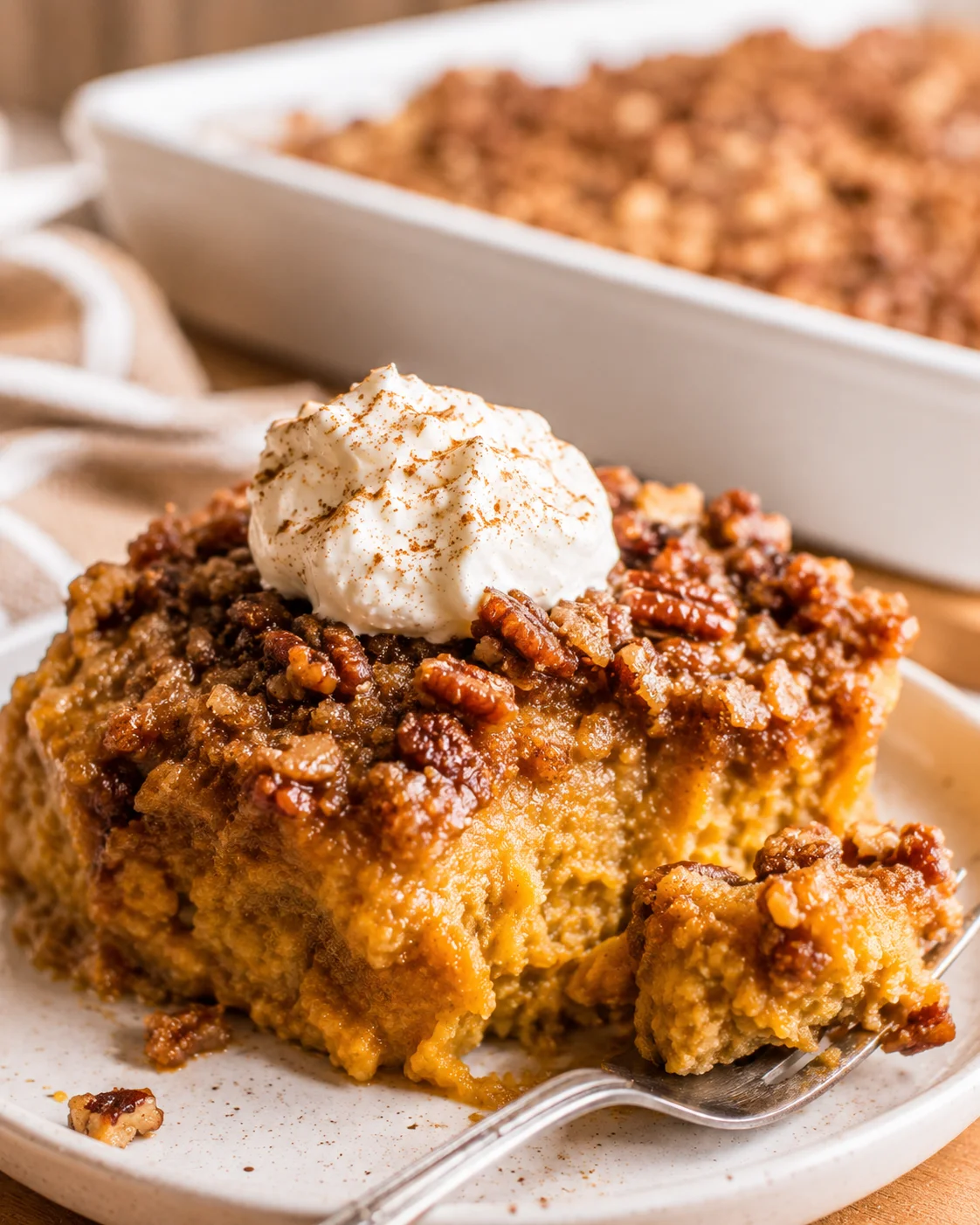 Close-up of pumpkin dump cake topped with whipped cream and pecans.
