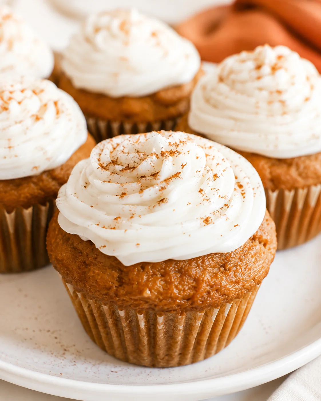 Close-up of moist, fluffy pumpkin cupcakes with dairy-free cream cheese frosting.