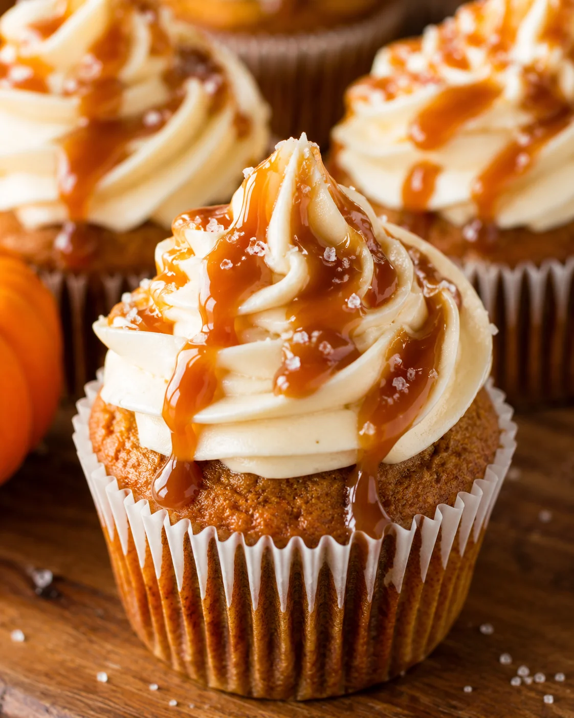 Close-up of moist pumpkin cupcakes topped with salted caramel frosting and drizzles