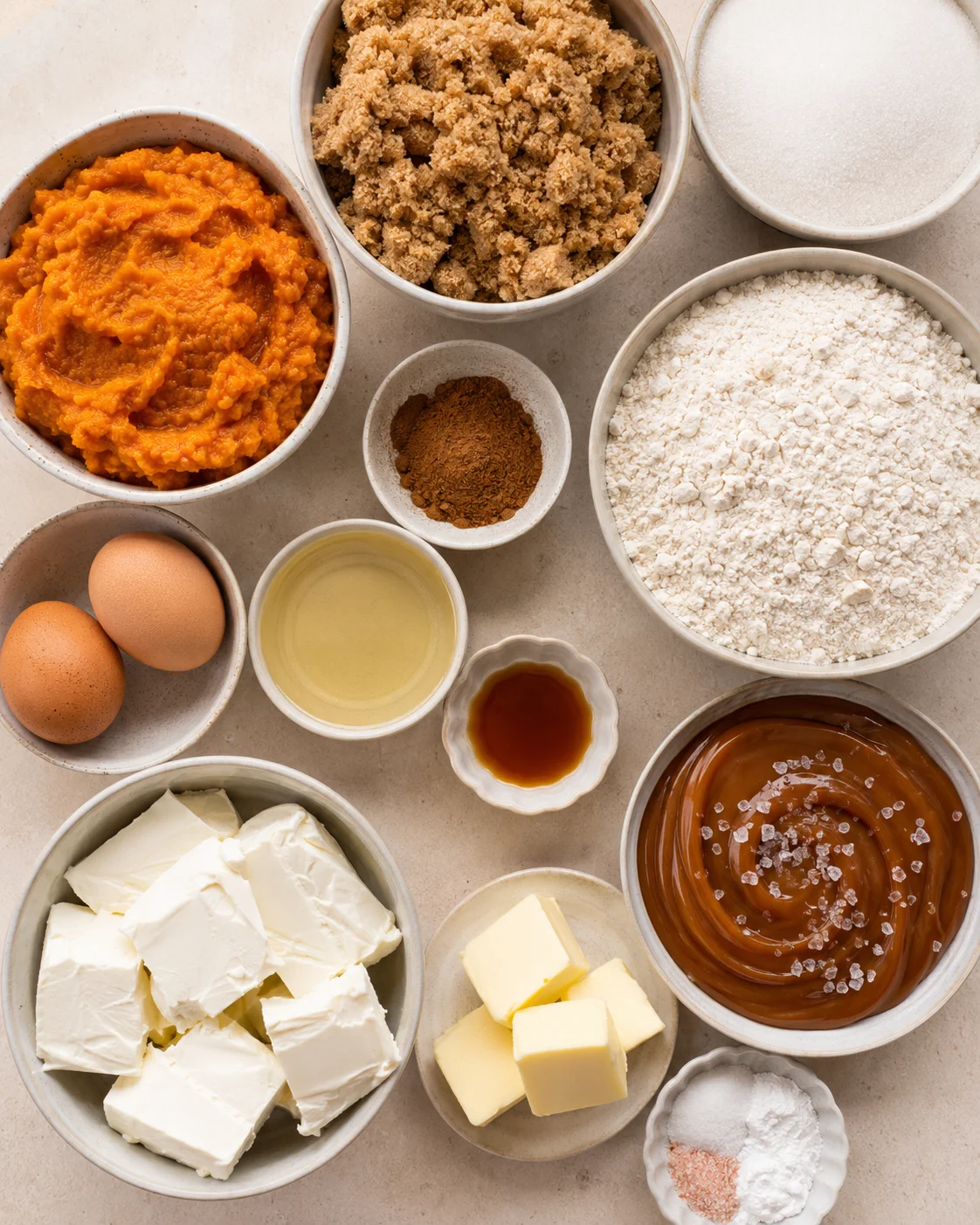 Assorted baking ingredients for pumpkin cupcakes with salted caramel frosting arranged on a countertop