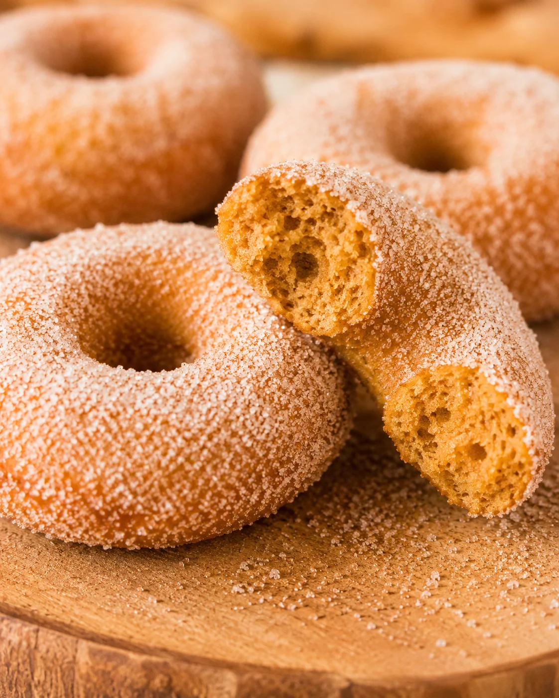 Close-up of cinnamon sugar-coated baked pumpkin donuts on a wooden surface
