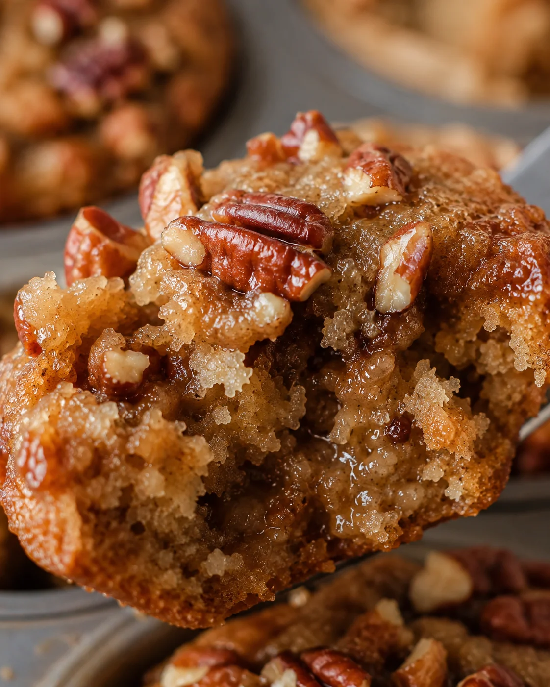 Close-up of a caramelized pecan muffin with a gooey center and crunchy topping