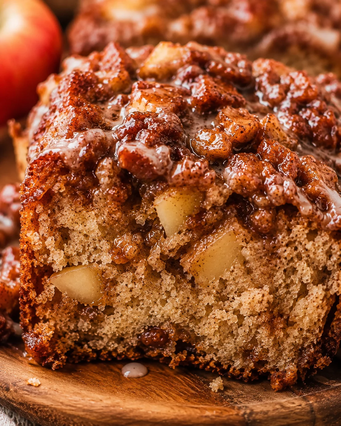 Close-up of moist apple bread topped with caramelized apple chunks and cinnamon sugar glaze.