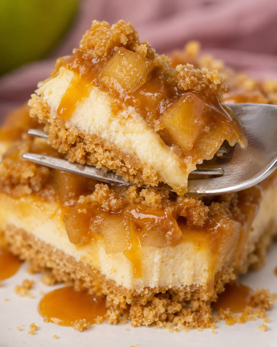 Close-up of a slice of caramel apple cheesecake bar with caramel drizzle and streusel topping