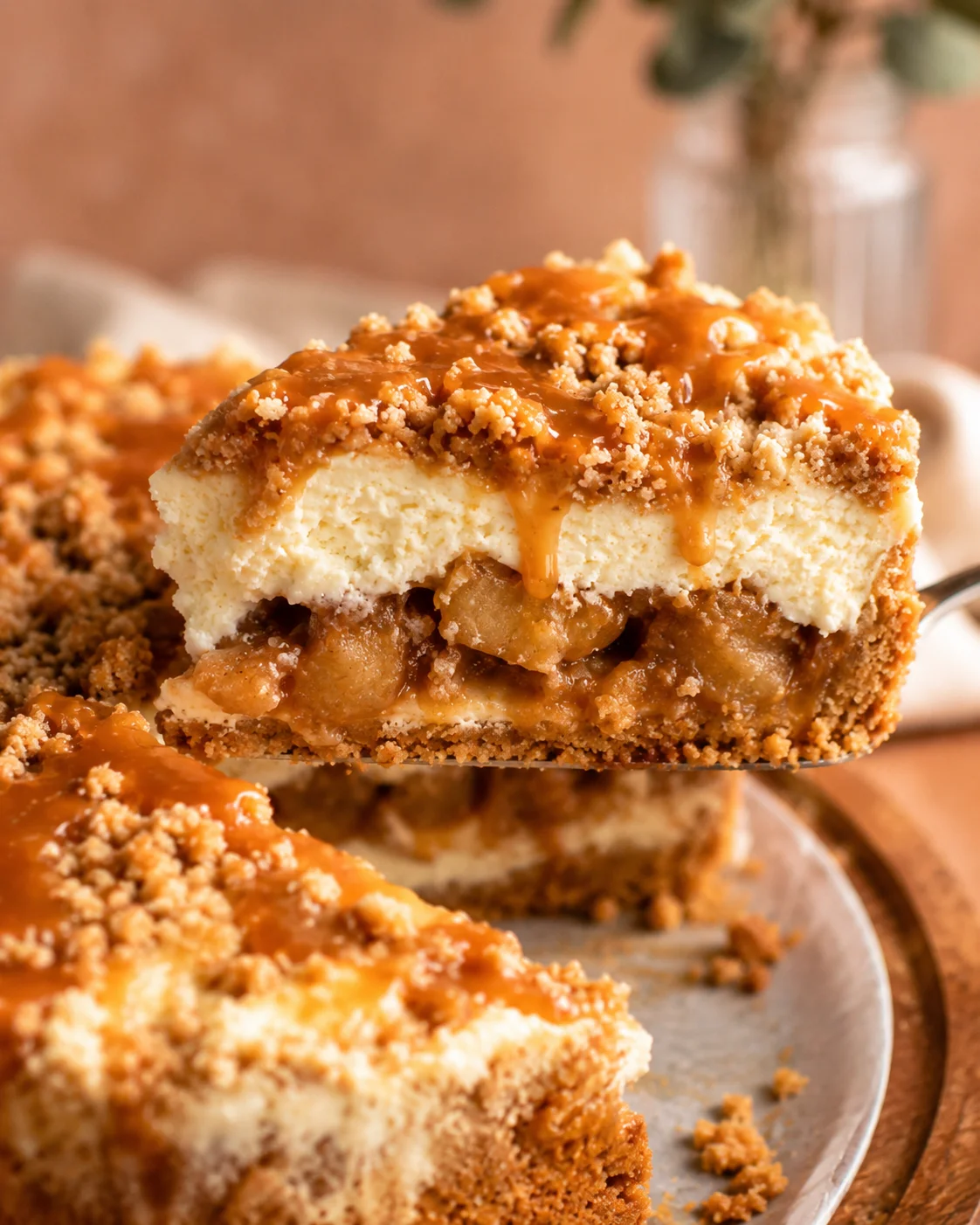 Close-up of a slice of apple crumble cheesecake with caramel drizzle and crumb topping