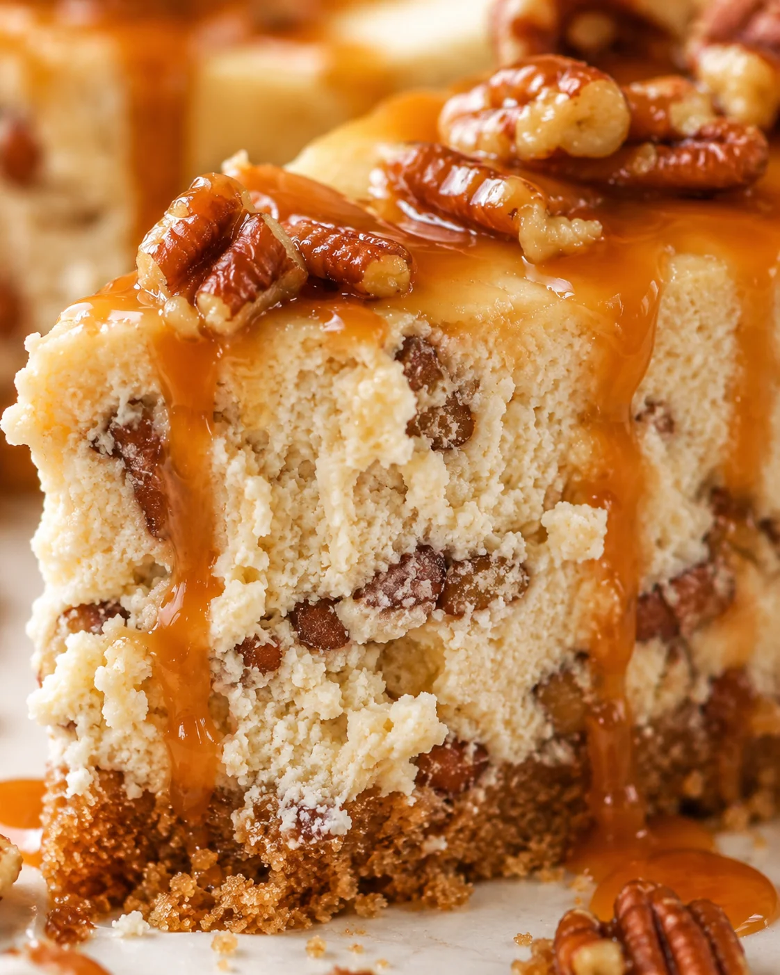 Close-up of a rich, creamy cheesecake topped with toasted pecans and caramel sauce.
