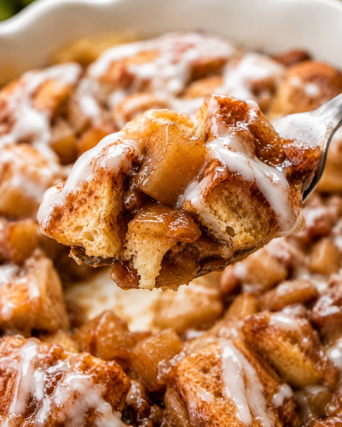 Close-up of a spoonful of apple cinnamon roll bake with apples and cinnamon rolls