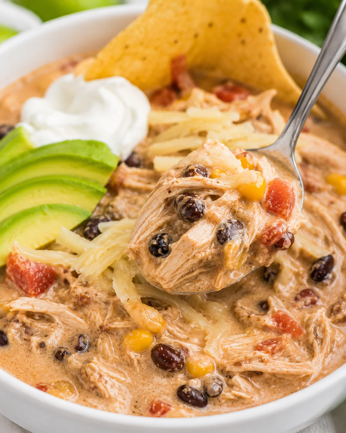 Hearty white chicken chili served with avocado, sour cream, and cheese in a bowl