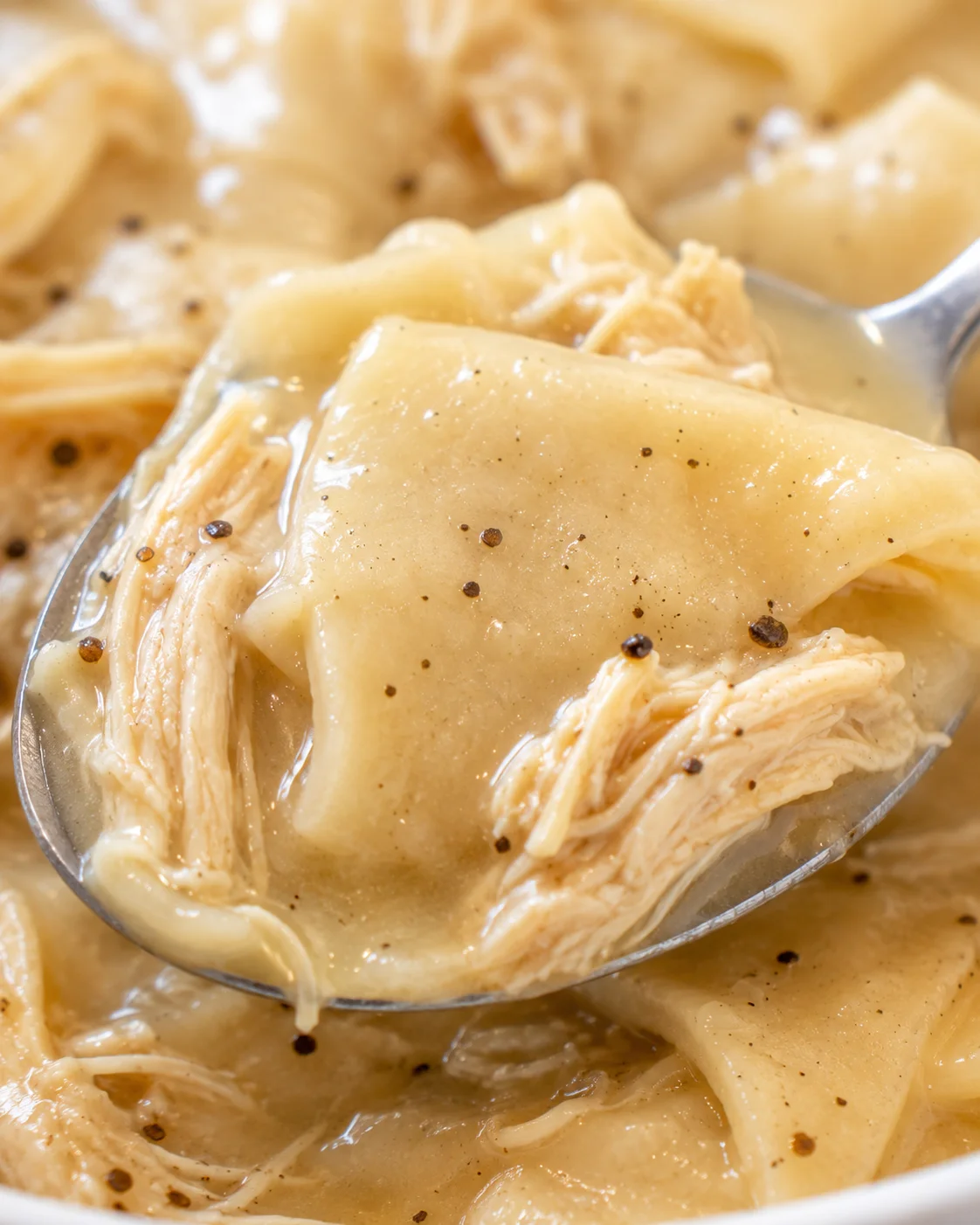 Close-up of fluffy homemade dumplings simmering in savory chicken broth.