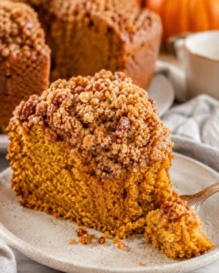 Delicious pumpkin coffee cake with crunchy streusel topping on a white plate.