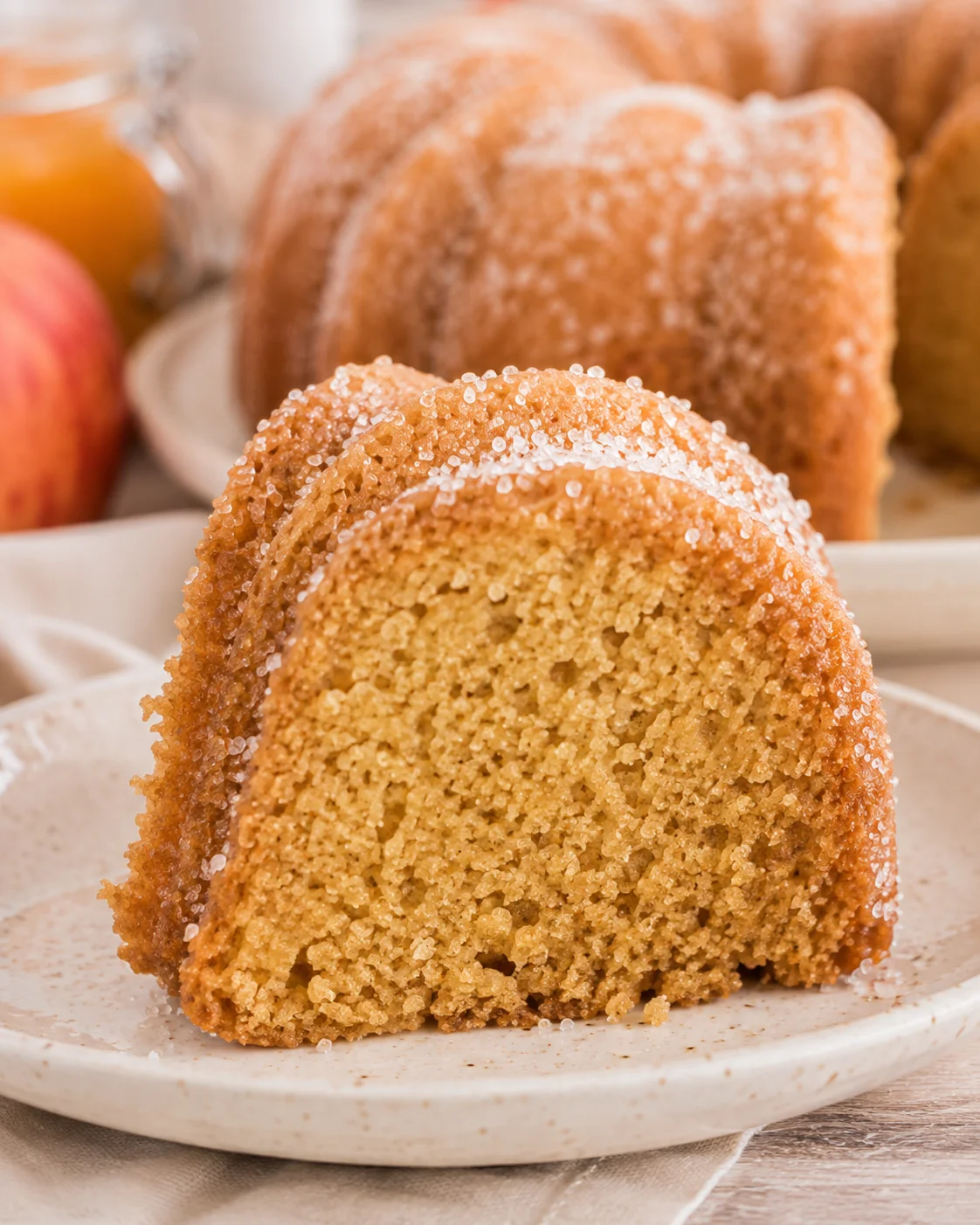 Slice of apple cider donut bundt cake on a plate showing moist crumb and sugar coating