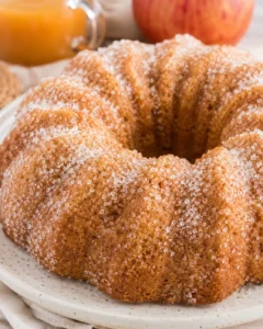 Whole apple cider donut bundt cake coated in cinnamon sugar on a plate