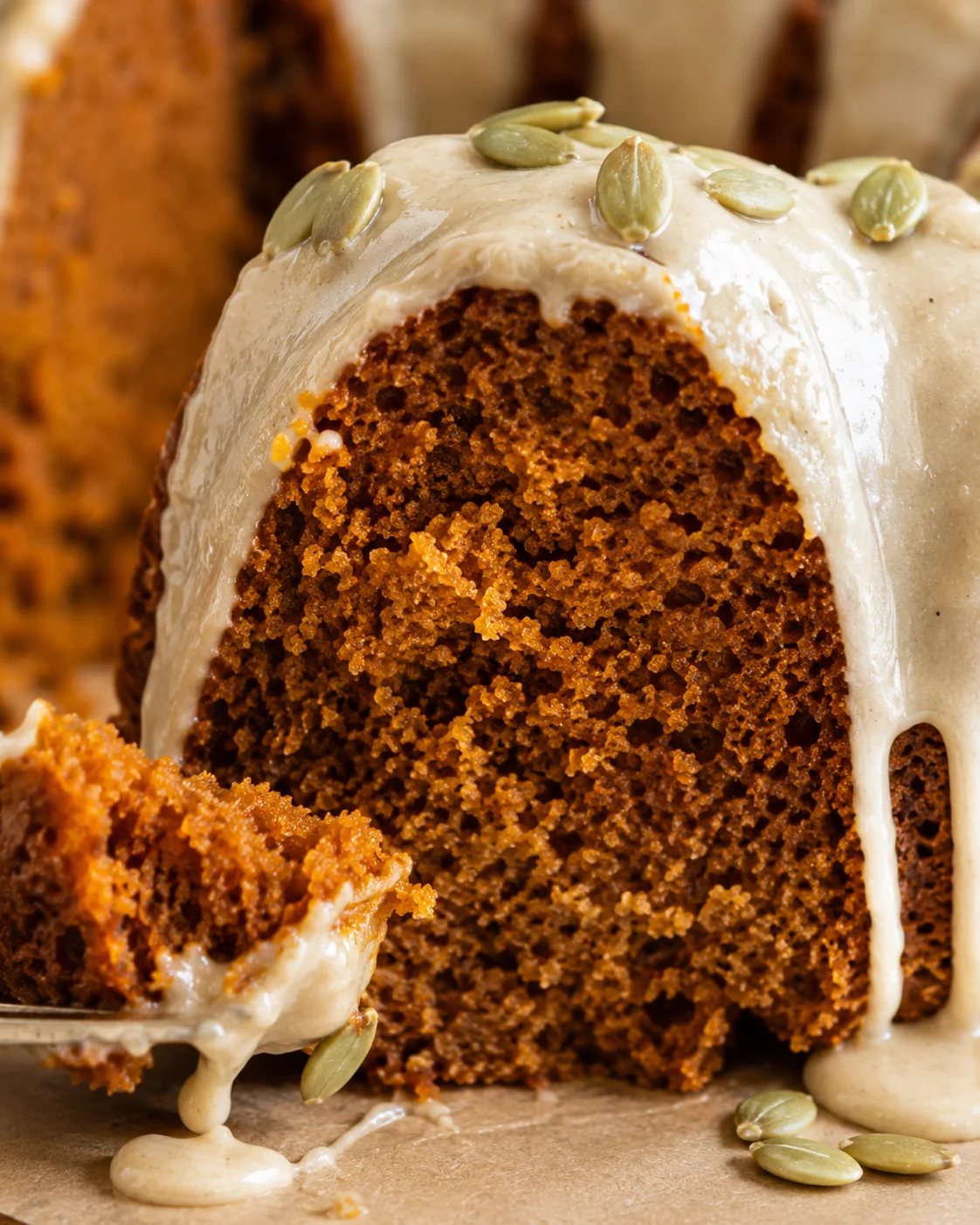 Moist pumpkin bundt cake topped with maple-brown butter glaze and pumpkin seeds