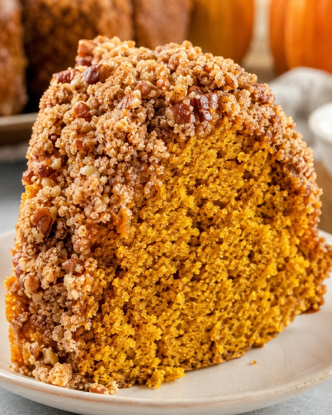 Delicious pumpkin coffee cake with a crumbly streusel topping, served on a white plate.
