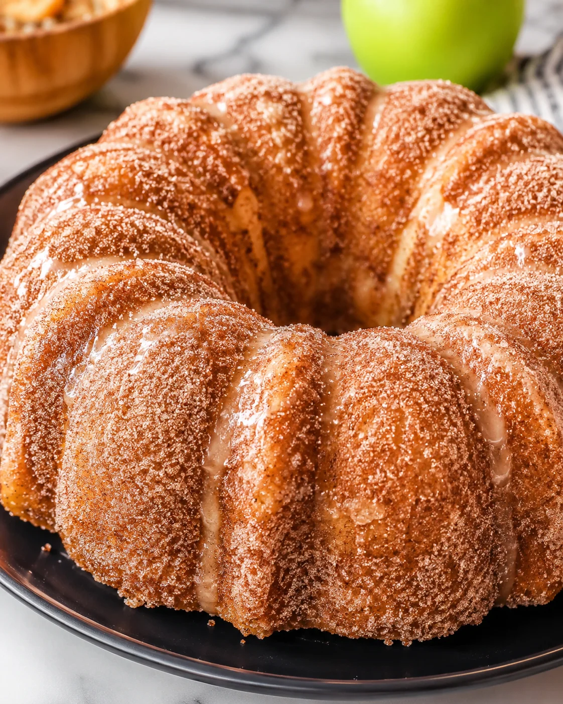 Close-up of a golden apple cider donut cake with cinnamon sugar topping